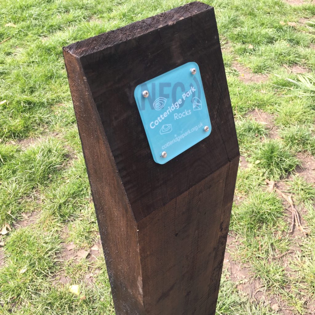 a wooden post with a green sign attached to it