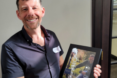 Chris with a photograph taken of him by the memorial tree planted in memory of his father, Christopher John Millward